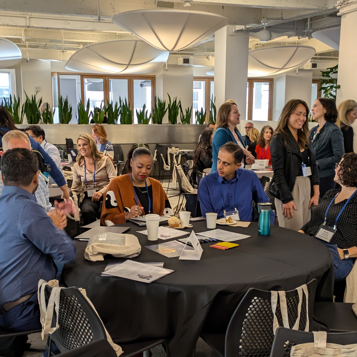 Diverse group of people gathered at round tables working together.