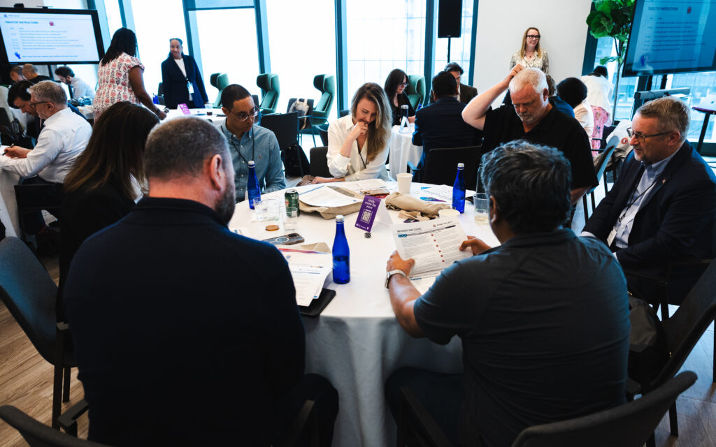 Group of professionals working at various round tables with papers and pens.