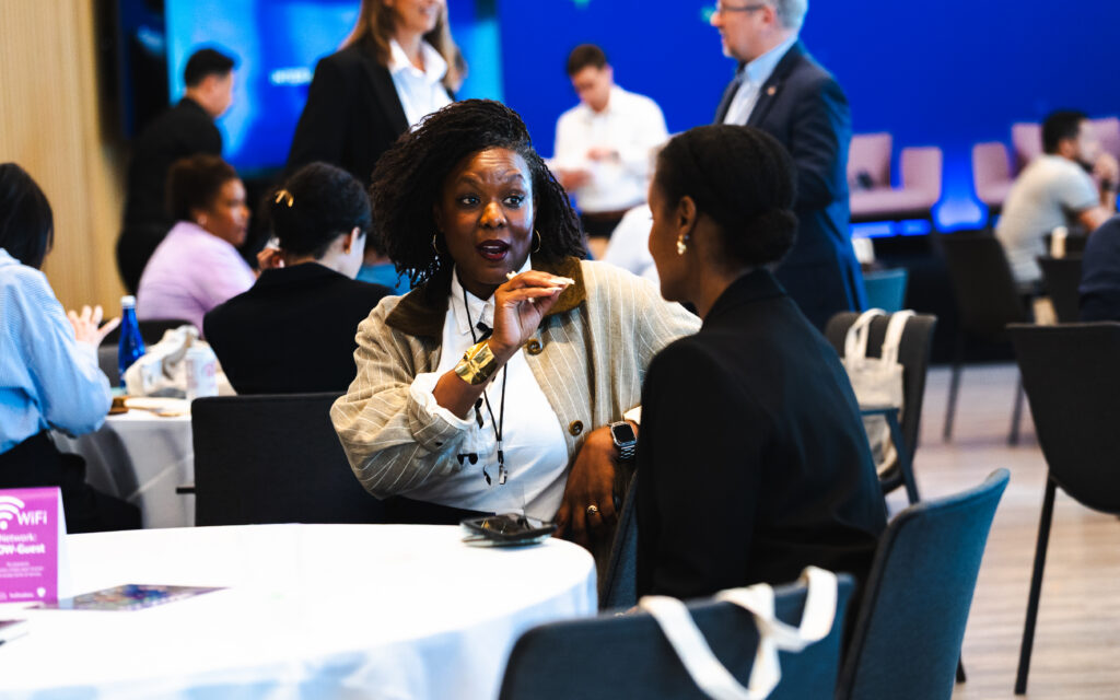 Two black women in professional dress talking over a table during a workshop.